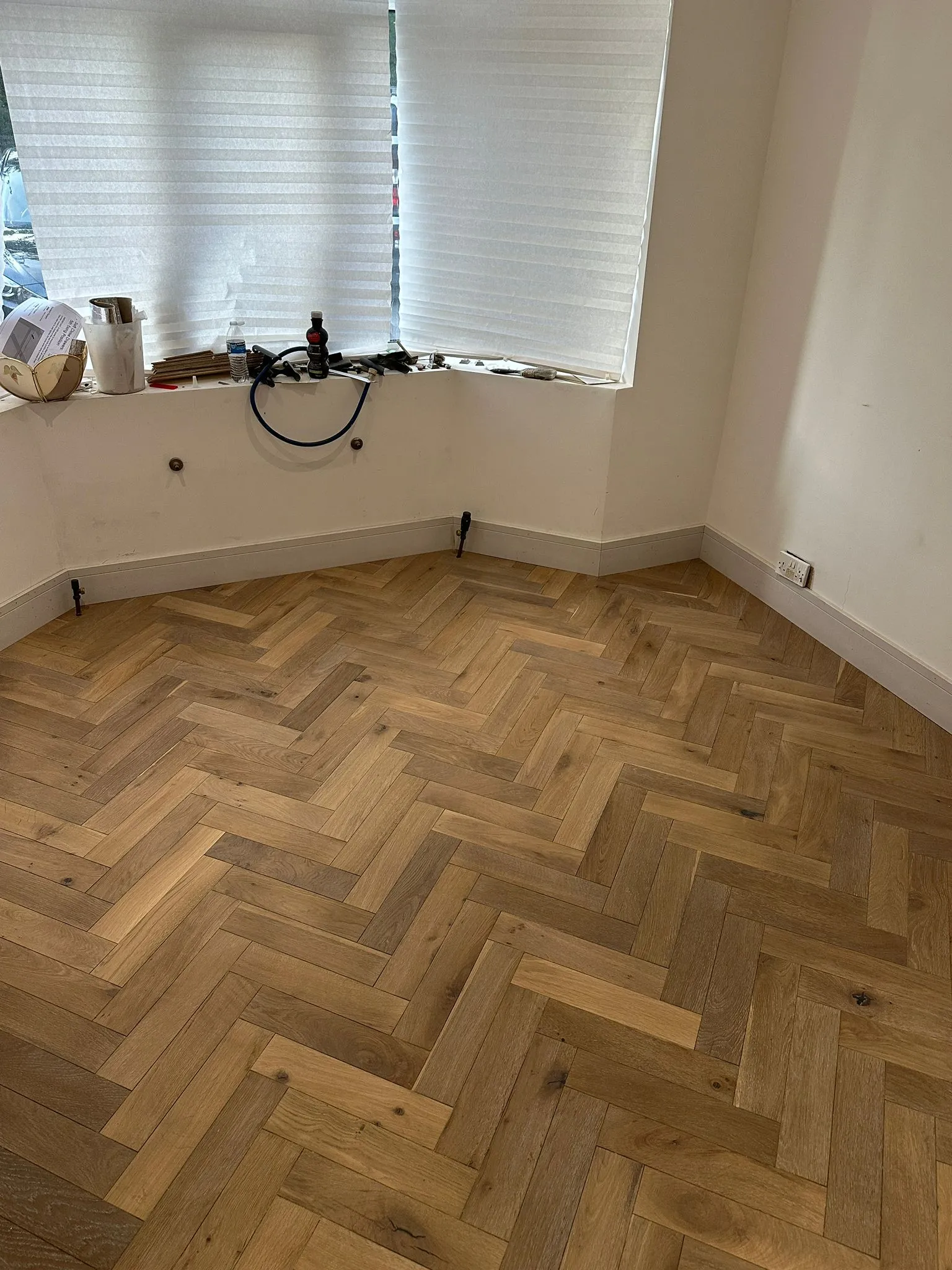 Herringbone oak flooring in room with bay window