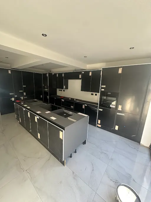 Dark fitted kitchen with island and marble floor