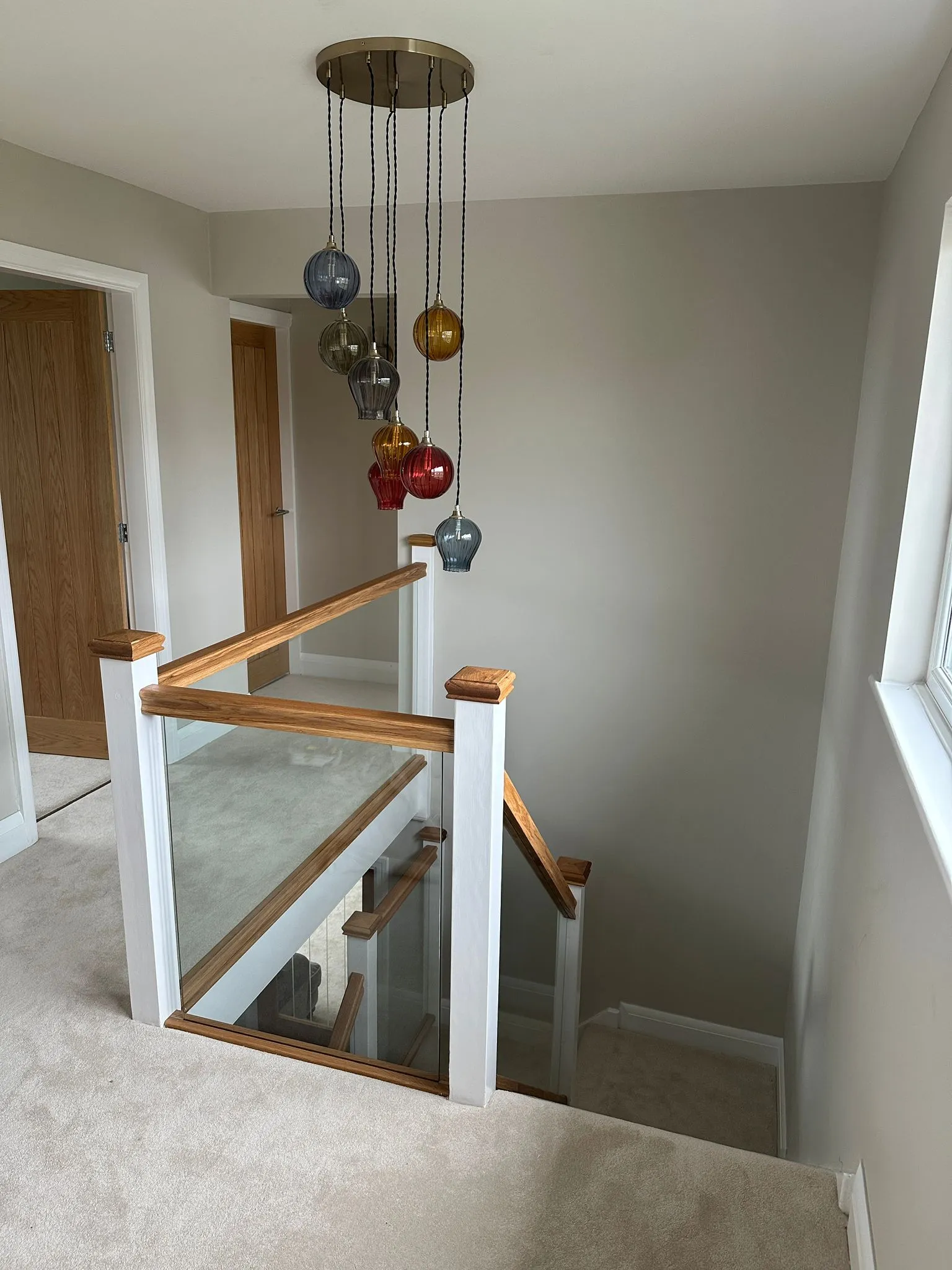 Oak and glass staircase from top landing with pendant chandelier