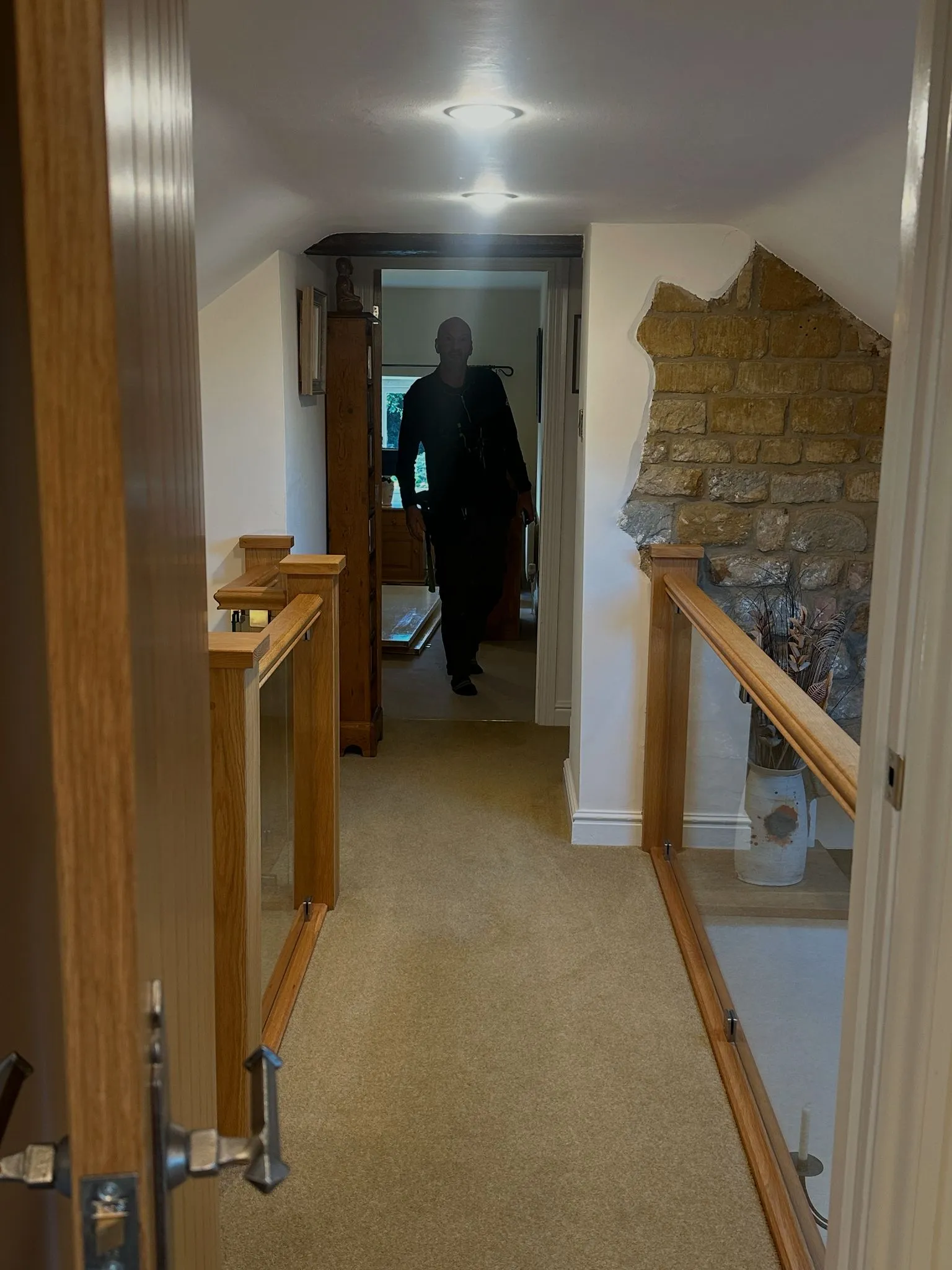 Oak and glass balustrade on landing with exposed stone wall