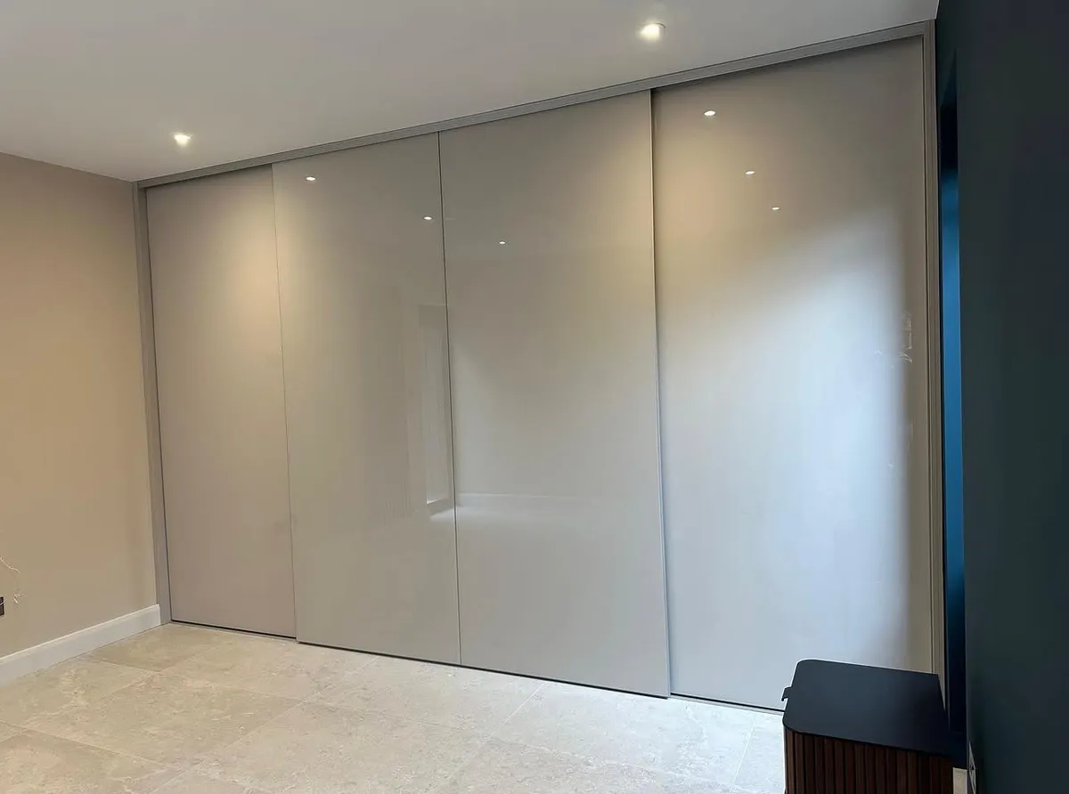 Fitted gloss sliding wardrobes with three panel doors