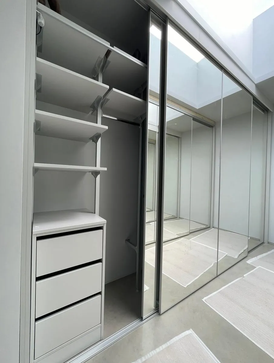 Walk-in wardrobe with mirrored sliding doors and built-in shelving